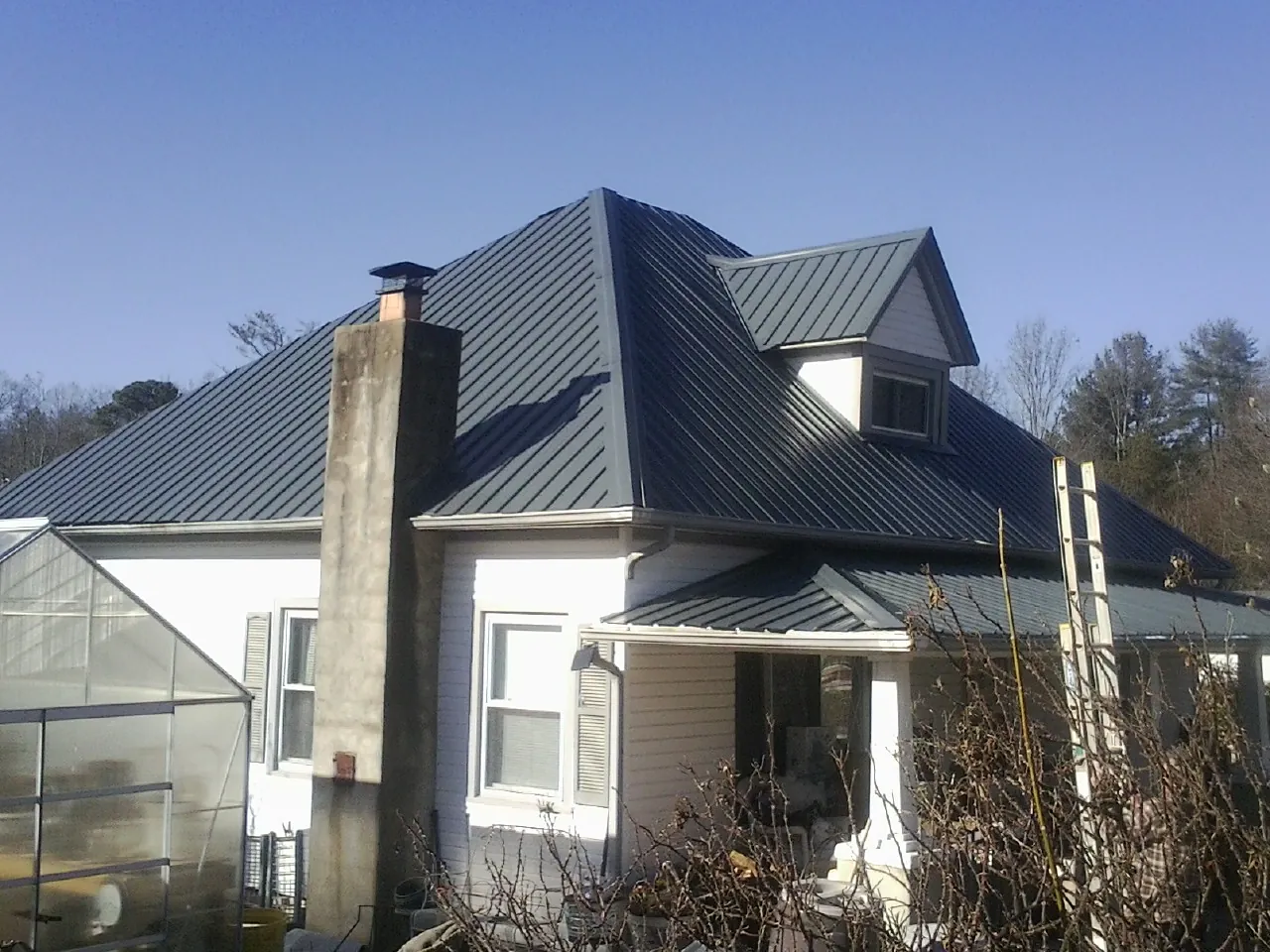 Dark blue standing seam metal roof on a white farmhouse with dormer — Slate & Tile Roof Repair by Roofing Brothers in Emlenton