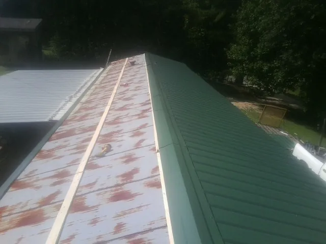 Old rusted panels beside newly installed green metal roofing — Wind Damage Roof Repair by Roofing Brothers in Emlenton