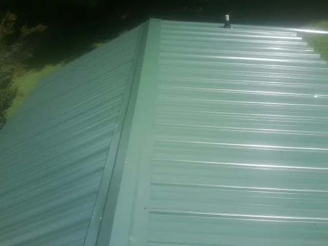 New green metal panels meeting at the ridge of a roof — Flat Roof Repair work by our crew in Emlenton