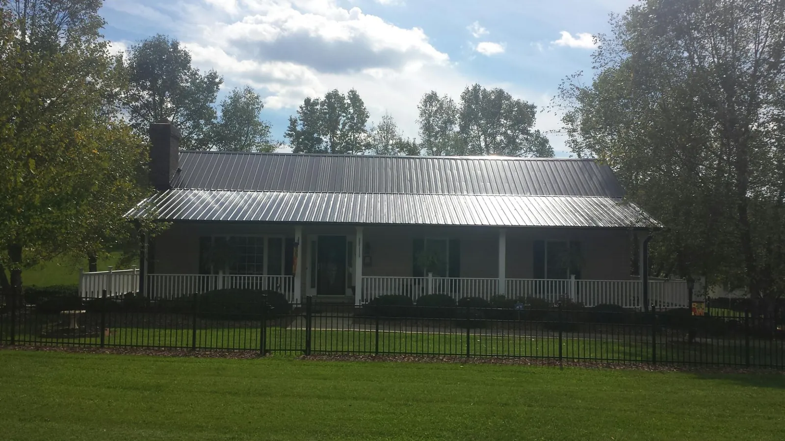 Gray metal roof on a brick ranch with a full width front porch — Gutter Guard Installation work by our crew in Emlenton