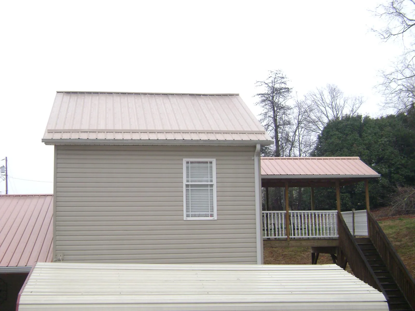 Tan metal roofs on a two story addition and attached porch, from a Roof Replacement job in Emlenton