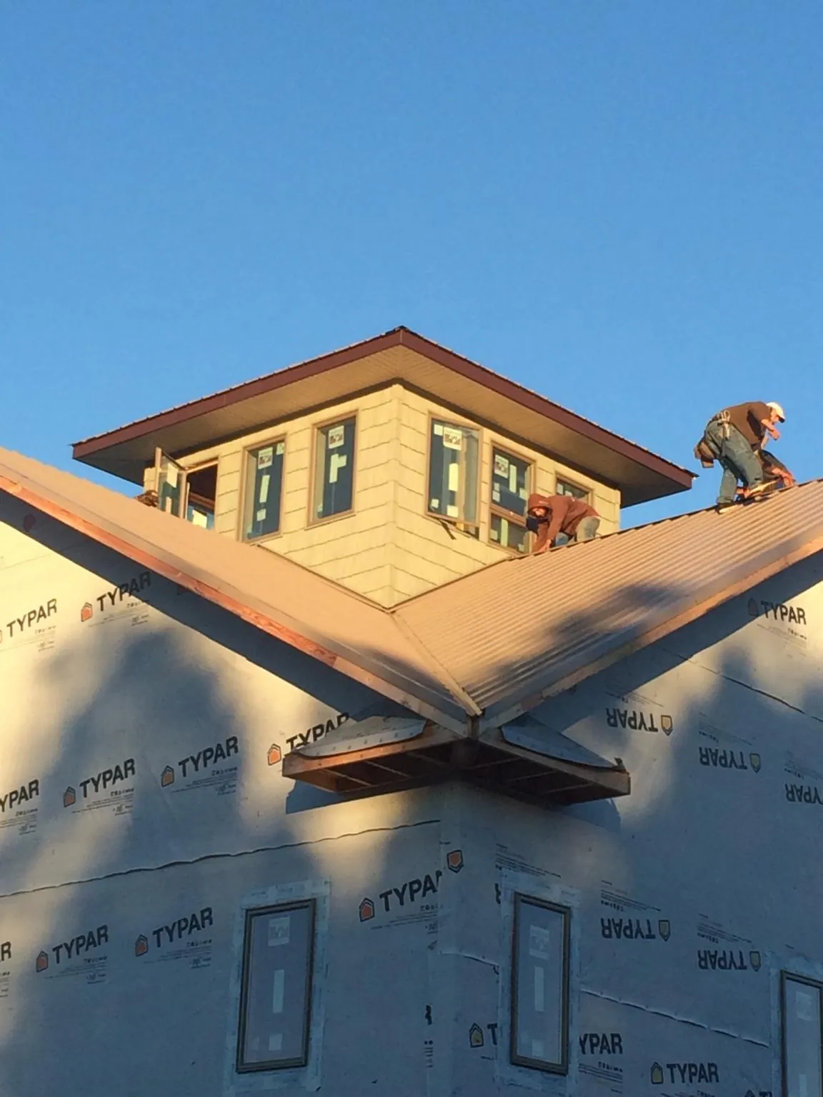 Roofers working around a rooftop cupola on a new metal roof at sunset — Roof Waterproofing in Emlenton by Roofing Brothers